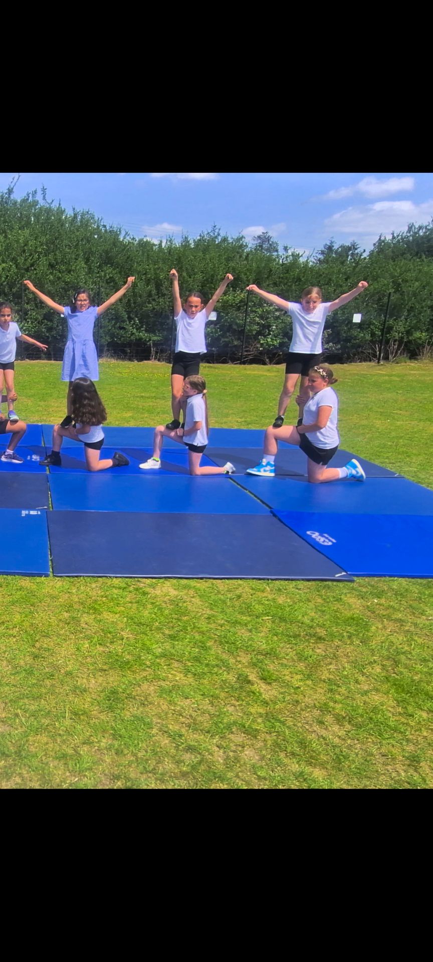 KSAL cheerleading club members performing an outdoor pyramid on mats at Girton Glebe Primary School
